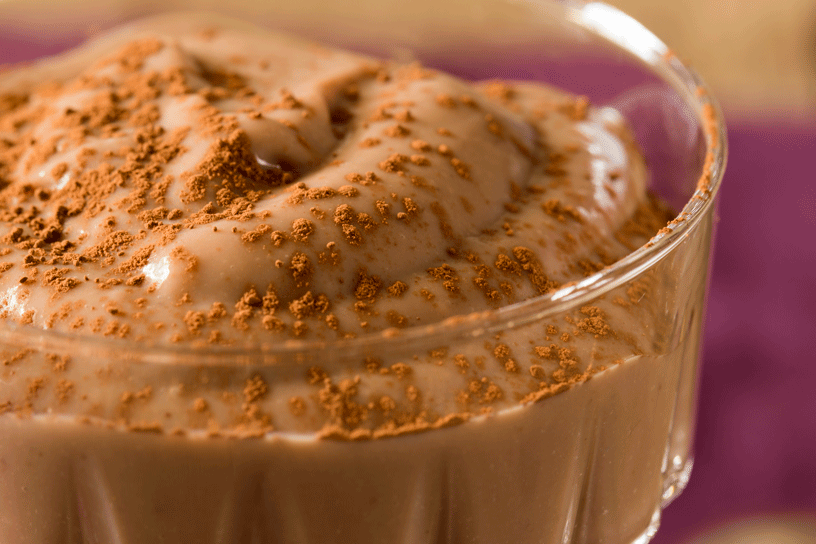 Zelfgemaakte chocoladevla bestrooid met cacaopoeder in glazen bakje